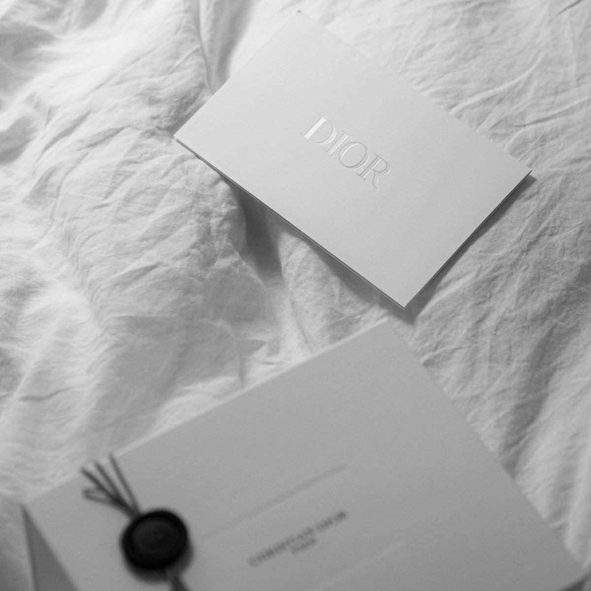 Dior gift box and card on white fabric.