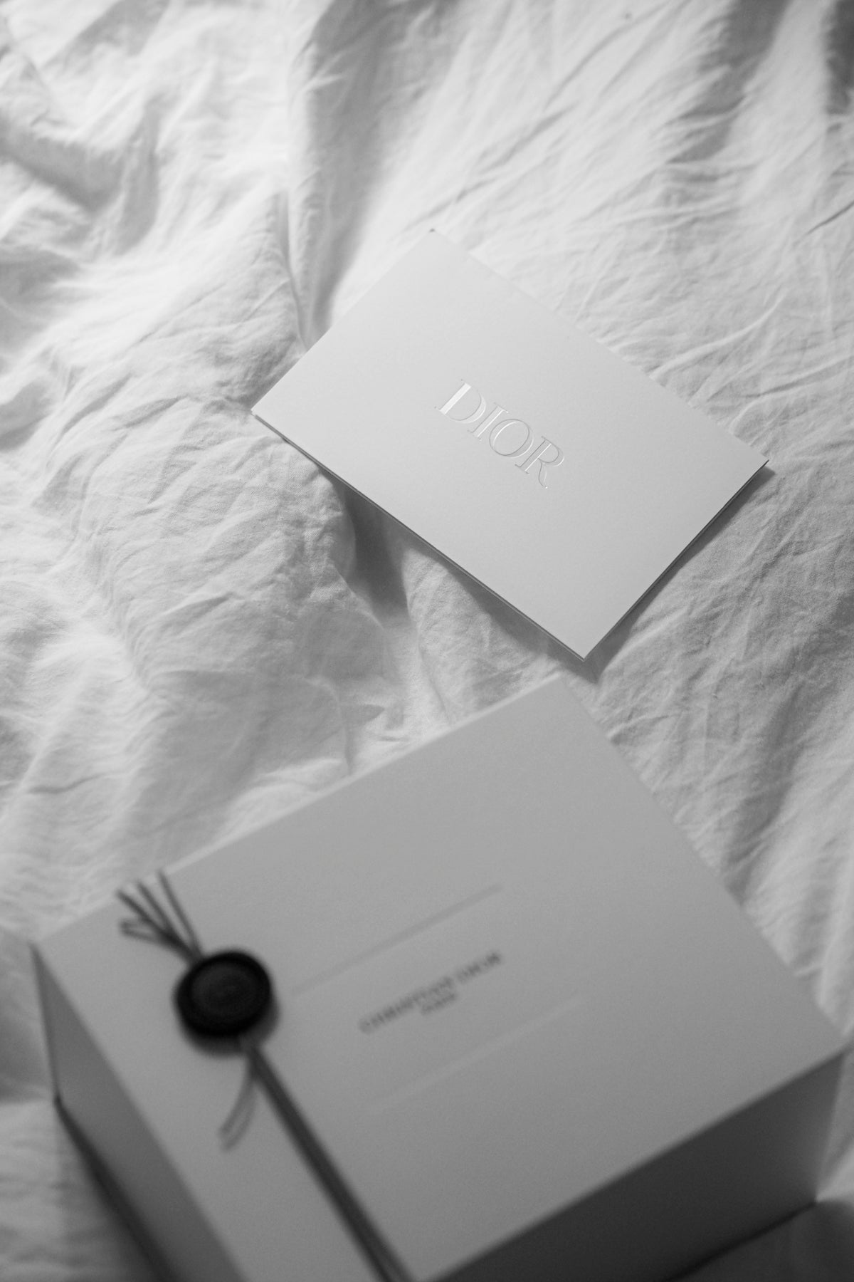 Dior gift box and card on white fabric.