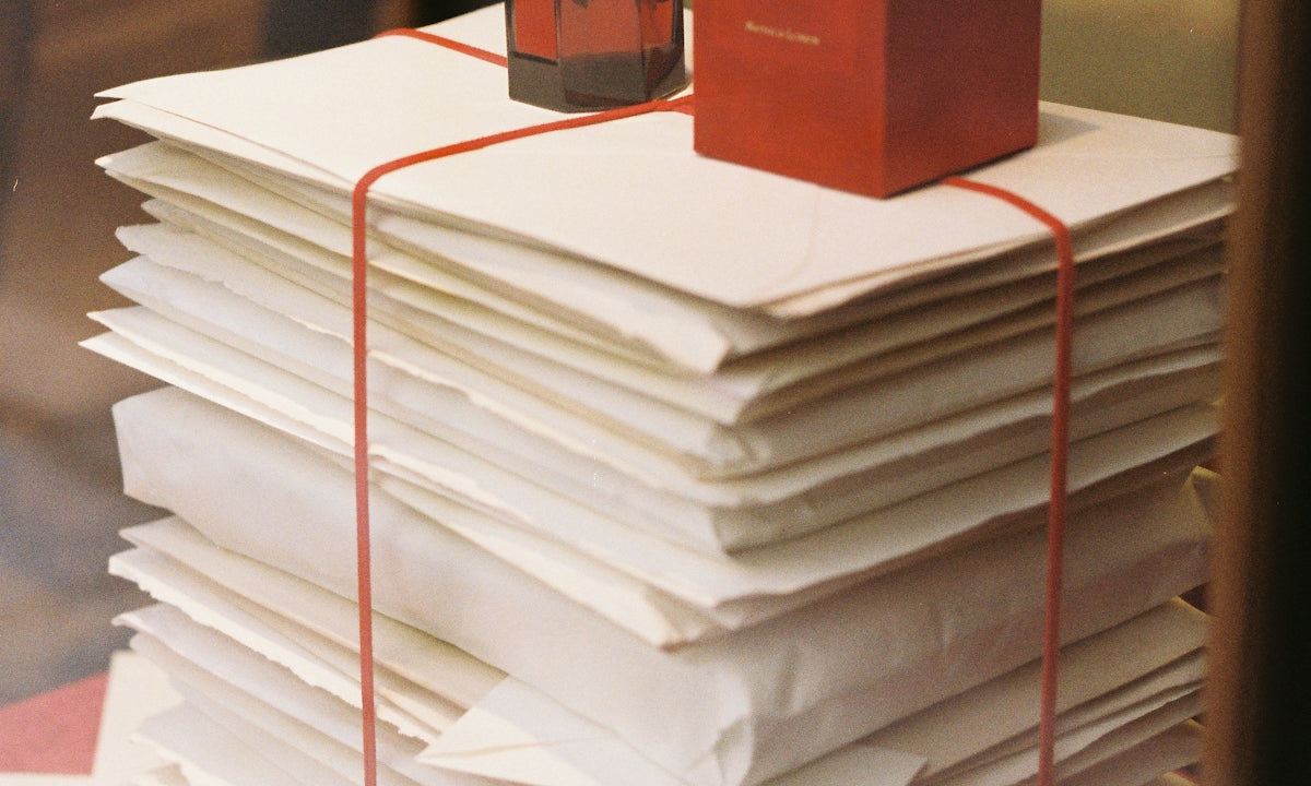 Stack of papers with perfume bottle and box