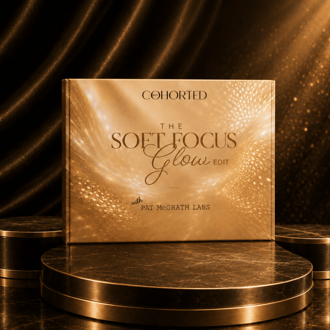 A square cosmetic-style box or book cover standing upright on a round metallic pedestal, with the text 'COHORTED THE SOFT FOCUS Glow EDIT' and 'PAT McGRATH LABS' visible. The design is predominantly warm metallic gold and bronze with glowing light effects, set against a dark draped background with gold highlights.